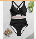 Black swimsuit with criss-cross straps on a textured white surface.