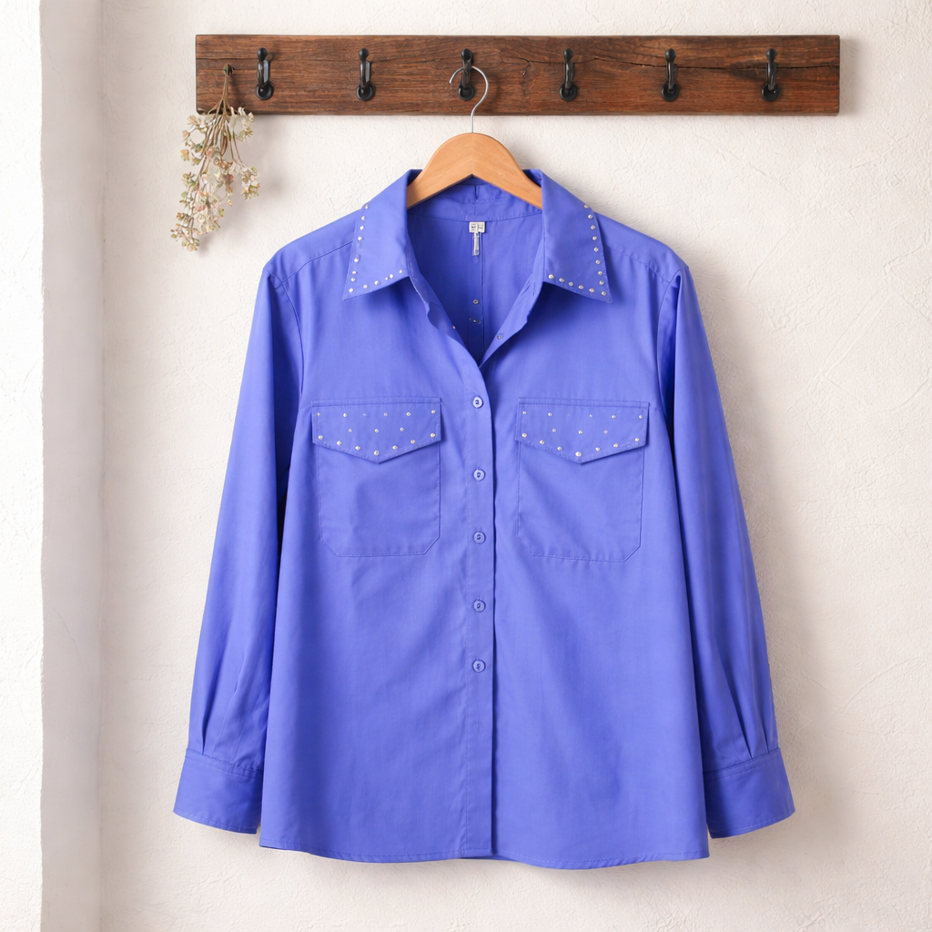 Blue shirt on a hanger against a beige wall with a wooden hook rack.