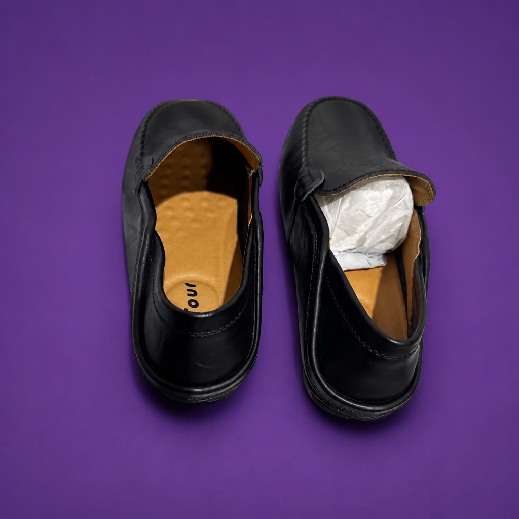 Black shoes with brown soles on a purple background