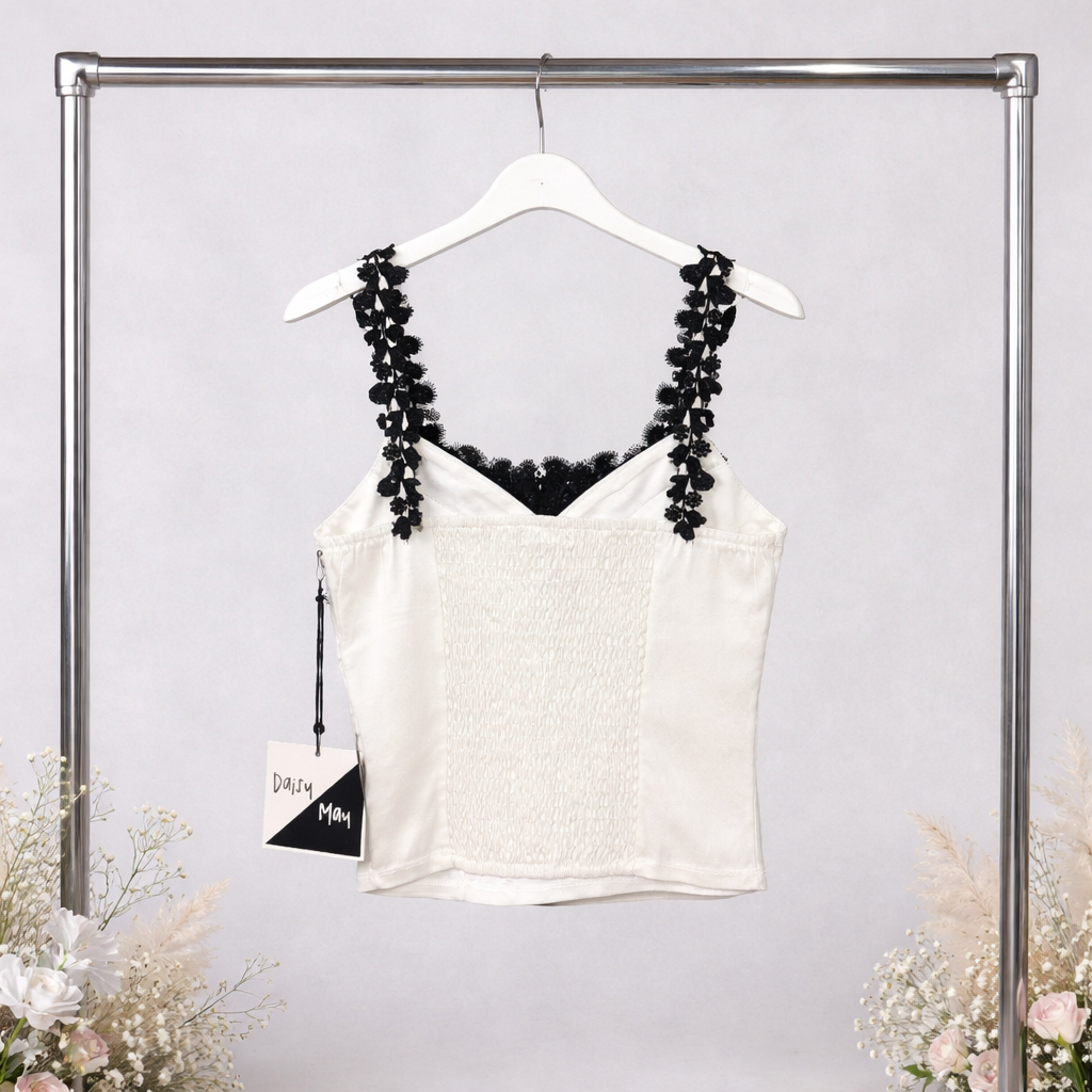White tank top with black lace details on a hanger against a light gray background.