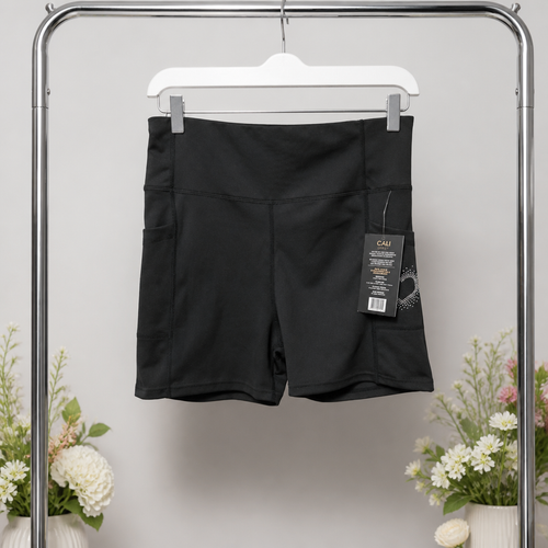 Black shorts with a tag on a hanger against a light gray background with floral decorations.