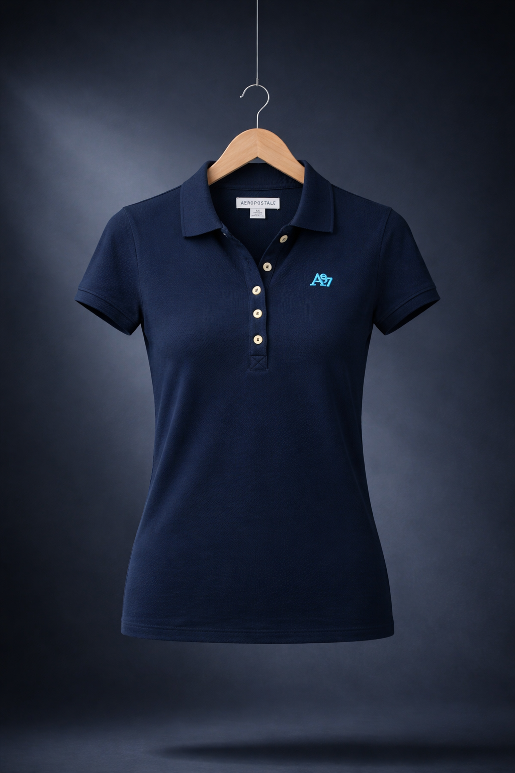 Navy blue polo shirt with a logo on a wooden hanger against a dark background