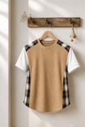 T-shirt with plaid sleeves hanging on a wooden hook against a white wall.