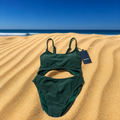 Green swimsuit on sand with ocean and blue sky in the background