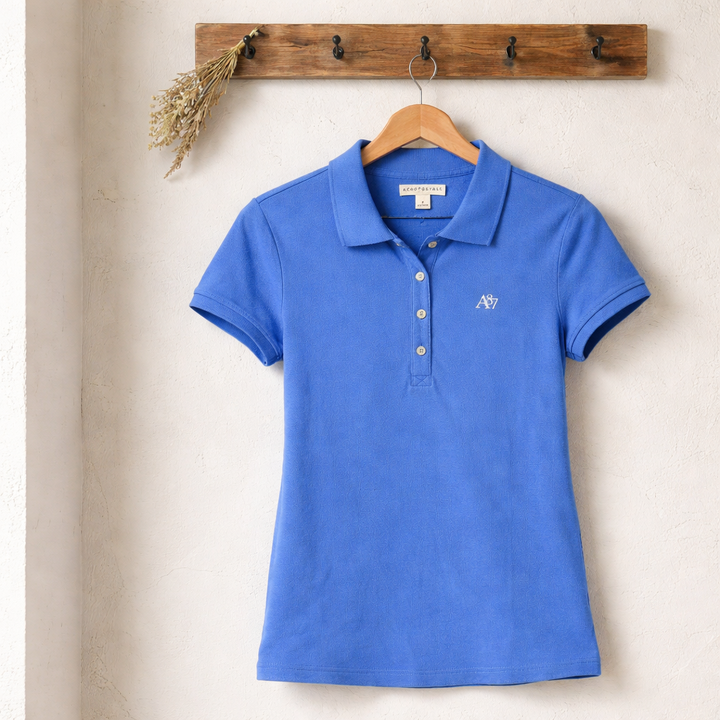 Blue polo shirt on a hanger against a beige wall