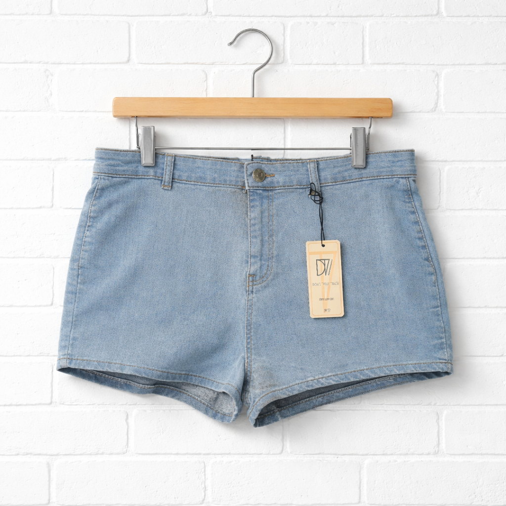 Light blue denim shorts on a hanger against a white brick wall.