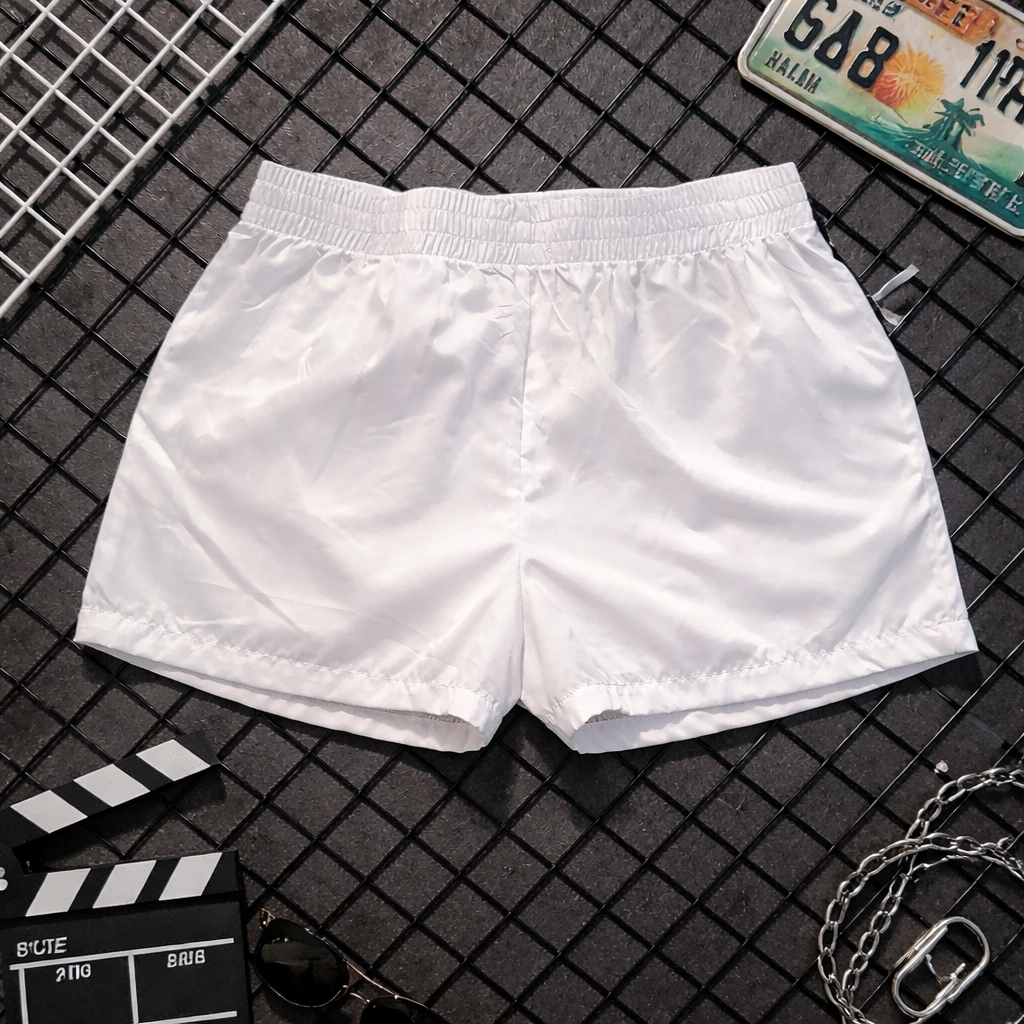 White shorts on a black grid surface with a license plate and clapperboard.