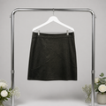 Black skirt on a hanger against a gray background with floral decorations.