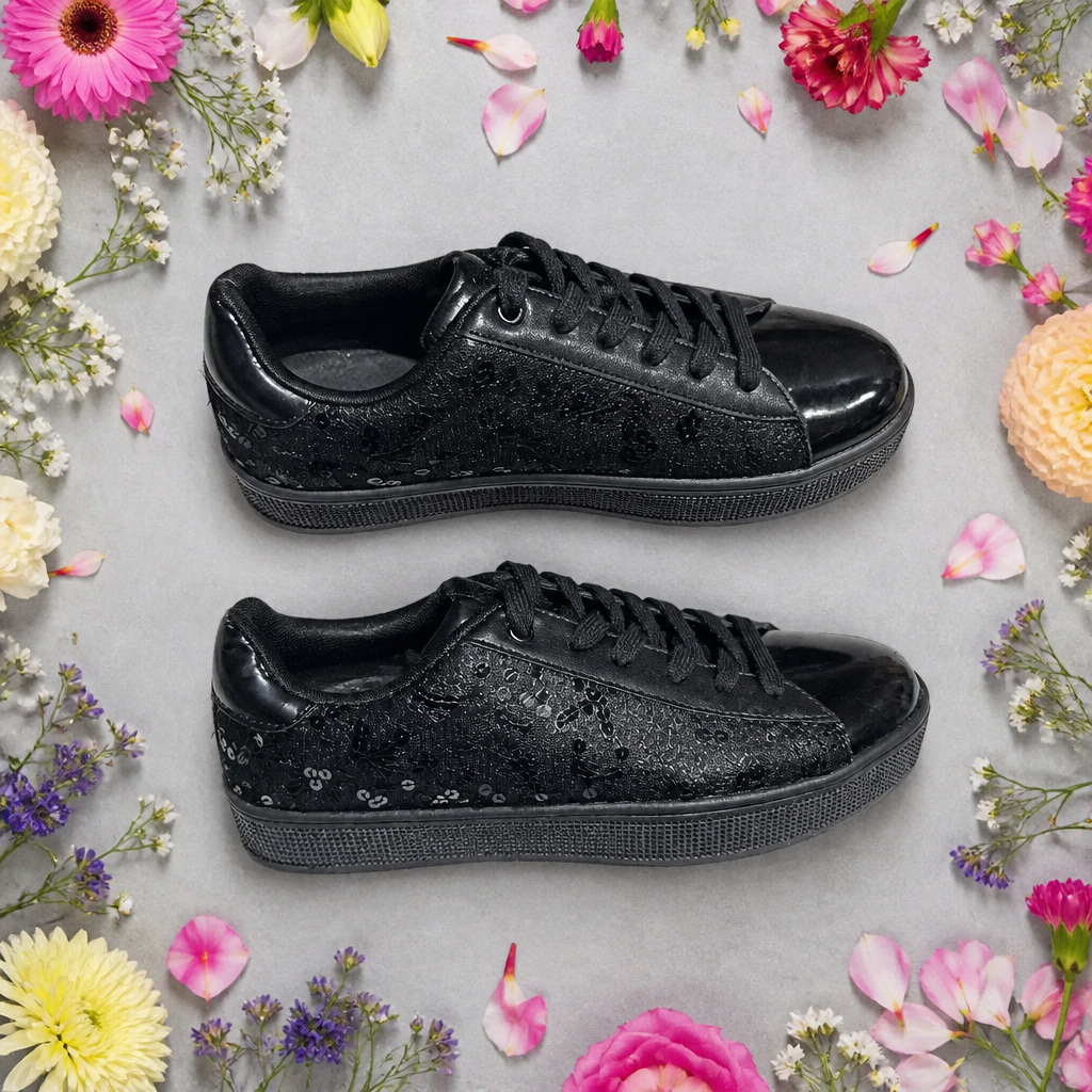 Black sneakers on a light gray background with colorful flowers around them