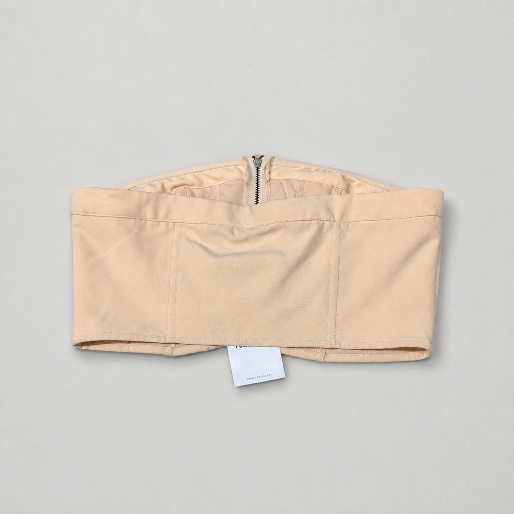 Back of a Beige strapless top with a tag on a gray background